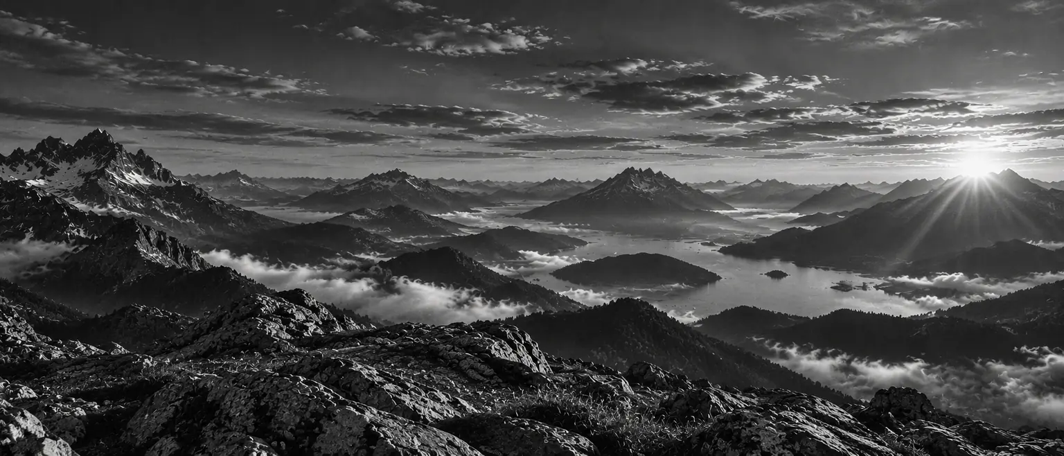 Sommets enneigés au lever du soleil au-dessus d’une mer de nuages, en noir et blanc