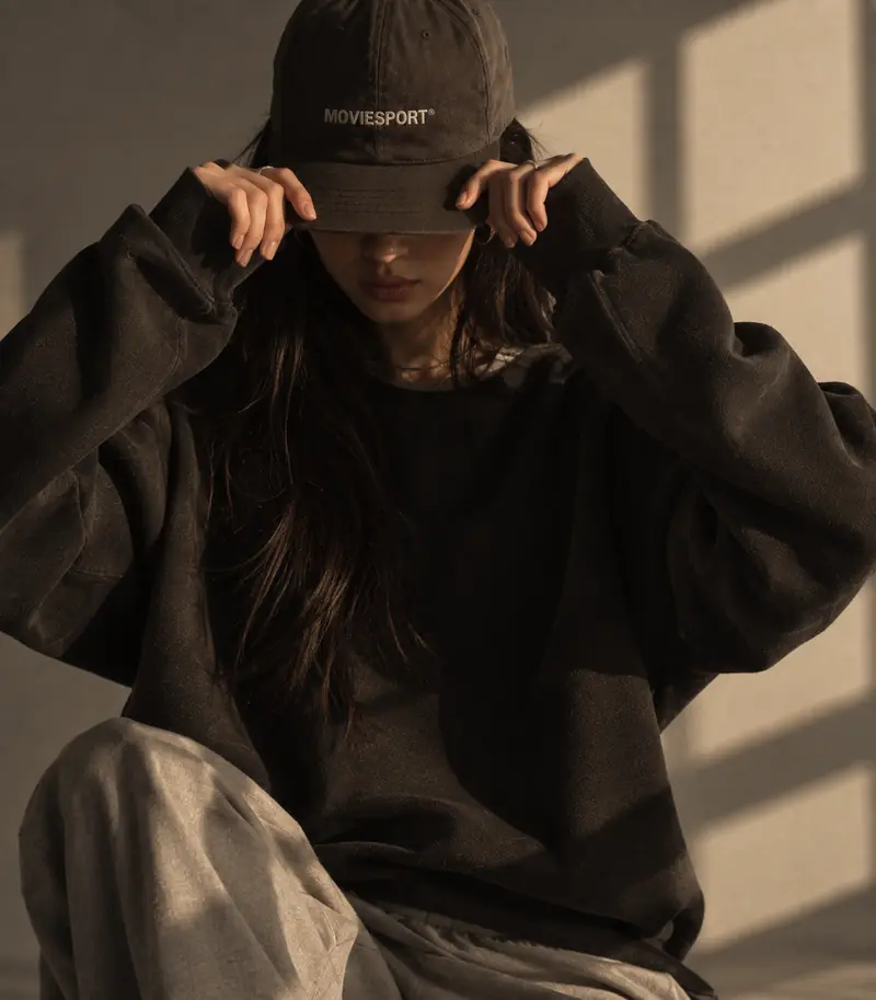 Femme accroupie portant une casquette MovieSport, lumière de fenêtre