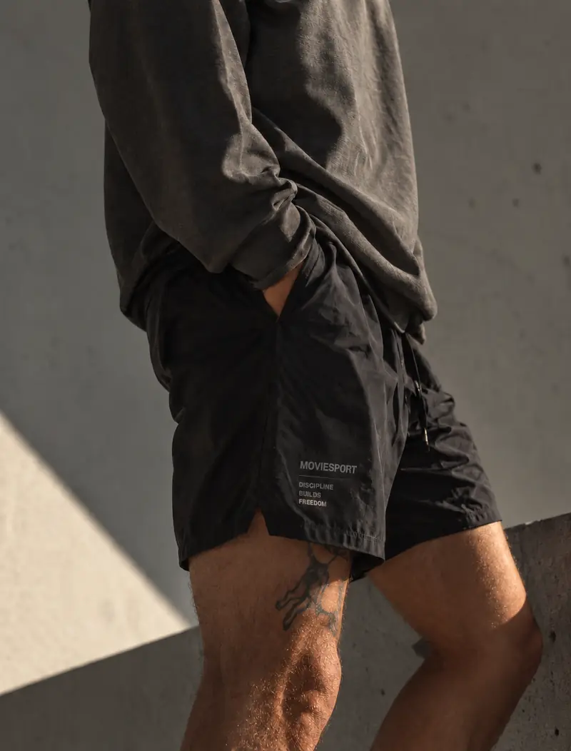 Pantalón corto de entrenamiento negro MovieSport contra un muro de hormigón